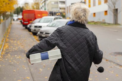 Margrit, freiwillige Fahrerin, hält die leere Box in den Händen und geht zurück zu ihrem Auto.